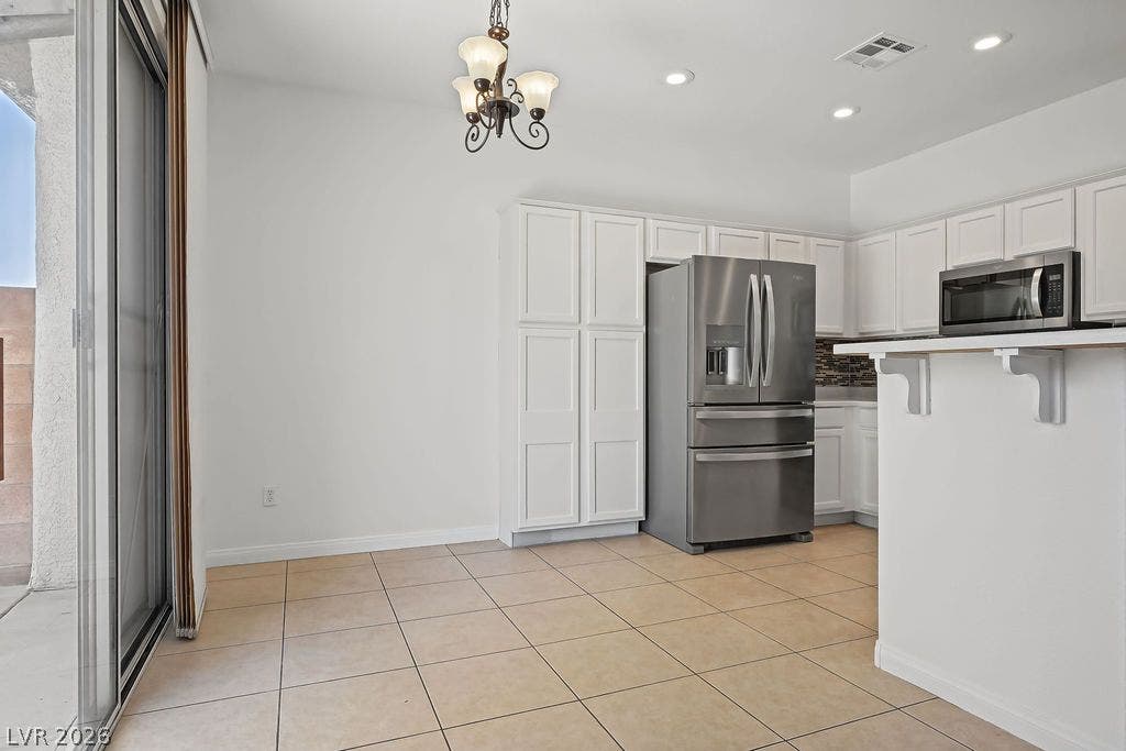 754 Solitude Point Avenue, Henderson, NV 89012 Tiled flooring and a sliding glass door enhance this functional kitchen and dining space.