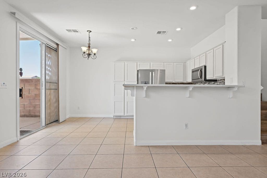 754 Solitude Point Avenue, Henderson, NV 89012 Tiled floors and white cabinetry frame a bright, functional kitchen space beside sliding glass doors.