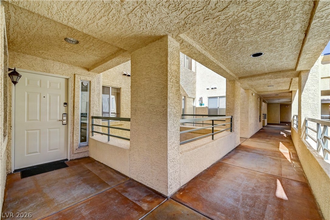 Stucco pillars and concrete walkways frame a sheltered entry with structured architectural lines.