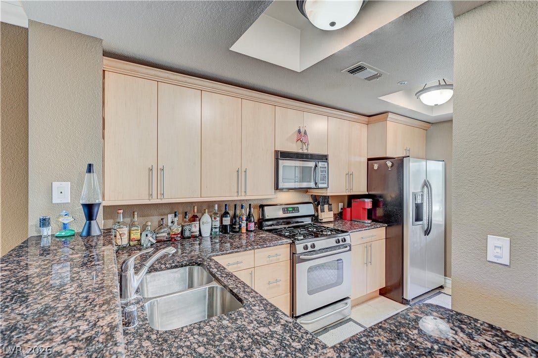 Gleaming stone countertops and classic wood cabinetry enrich this functional, modern cooking space.