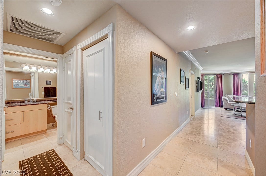 Polished tile flooring and recessed lighting line the hallway leading into the living spaces.