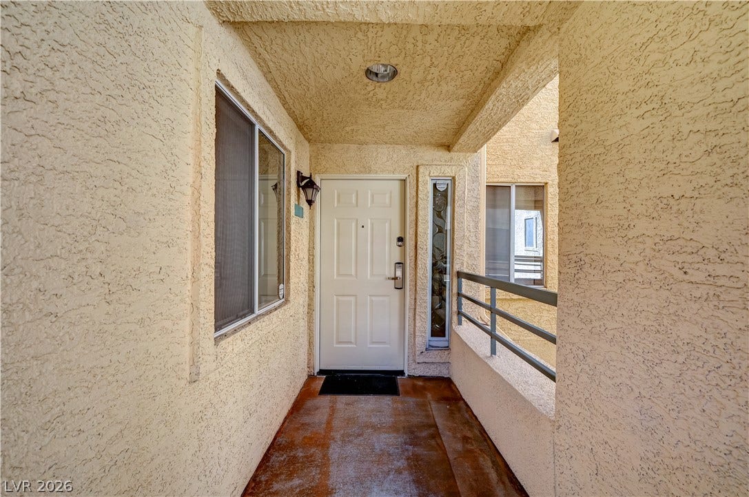 Textured stucco walls line a private covered entrance leading to the front door.