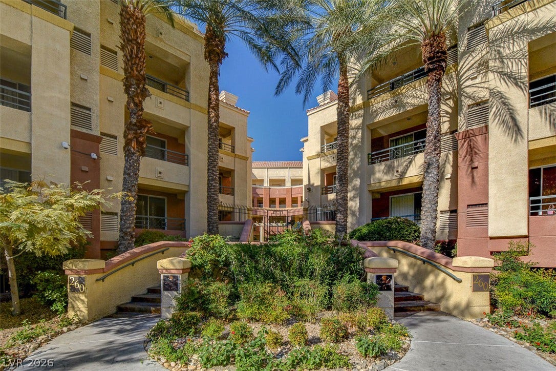 Palm trees frame the landscaped concrete entry paths of this multi-level residential building.