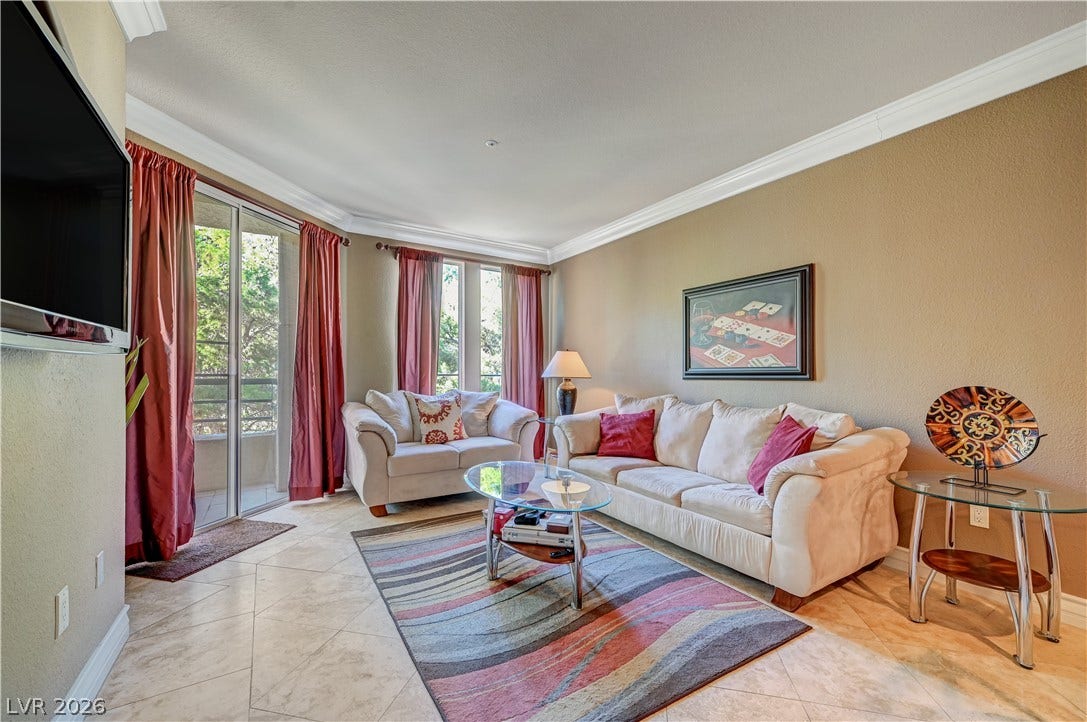Crown molding frames the tiled living area leading out to a private balcony.