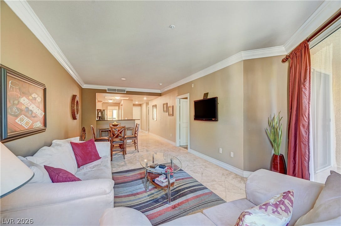 An open living area showcases polished tile flooring and detailed crown molding.