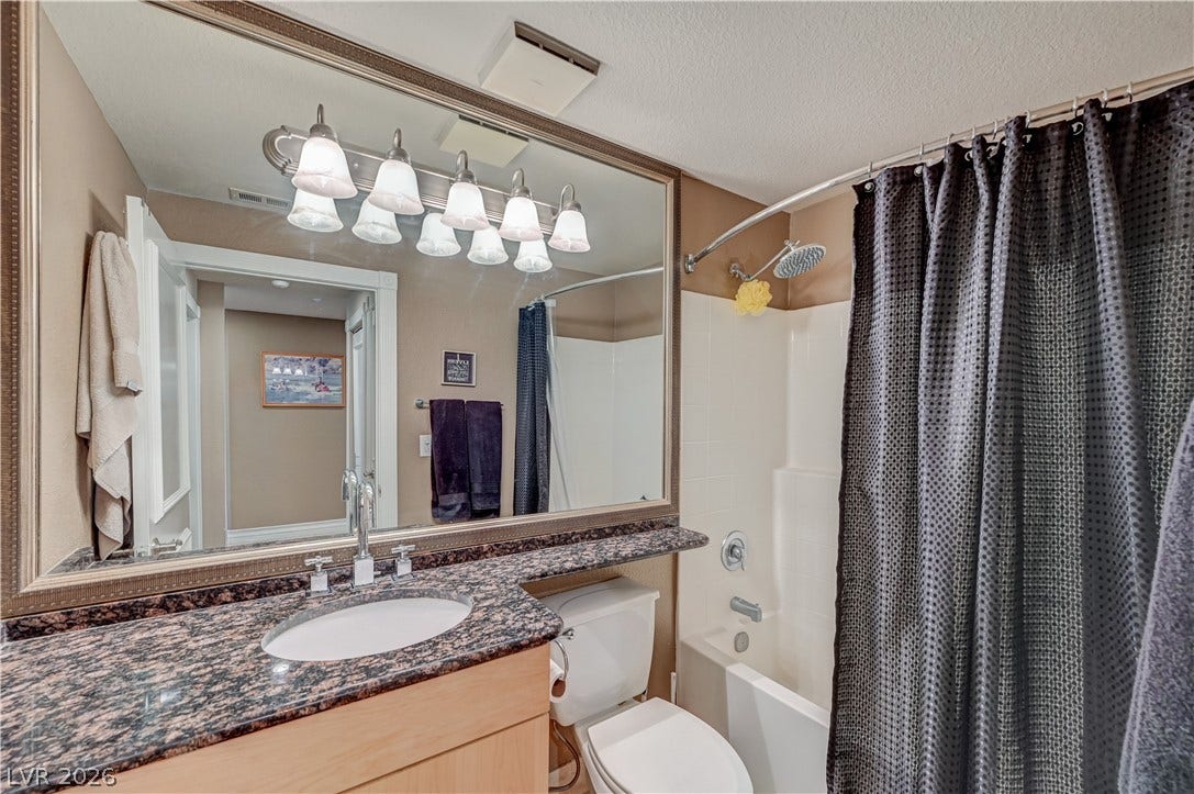 Granite counters and a framed mirror accent this well-appointed bathroom.