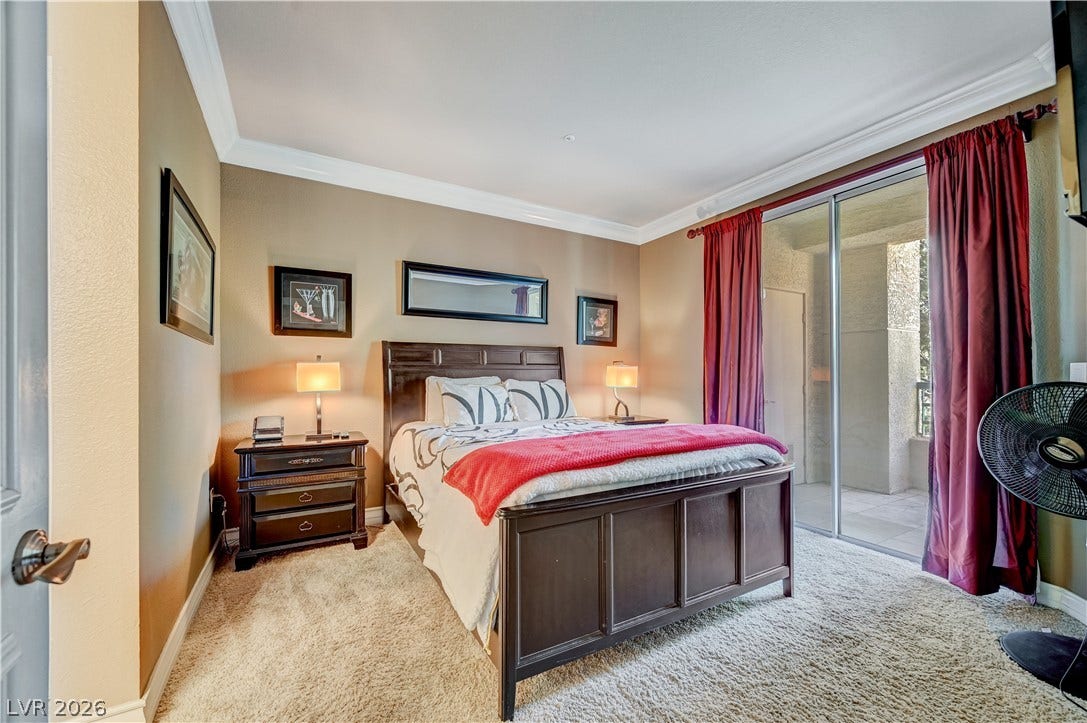 Plush carpeting and elegant crown molding frame this restful space featuring sliding glass doors.