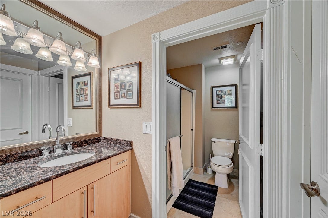 Polished granite countertops and classic wood cabinetry enrich this well-designed bathroom space.