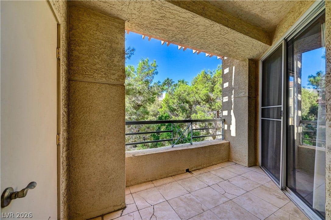 Tiled flooring and a secure railing frame serene views of mature green trees.