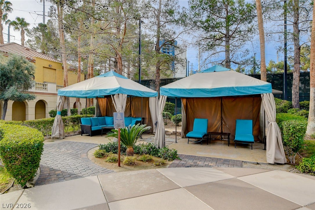Shaded poolside cabanas sit nestled within manicured landscaping and mature trees.