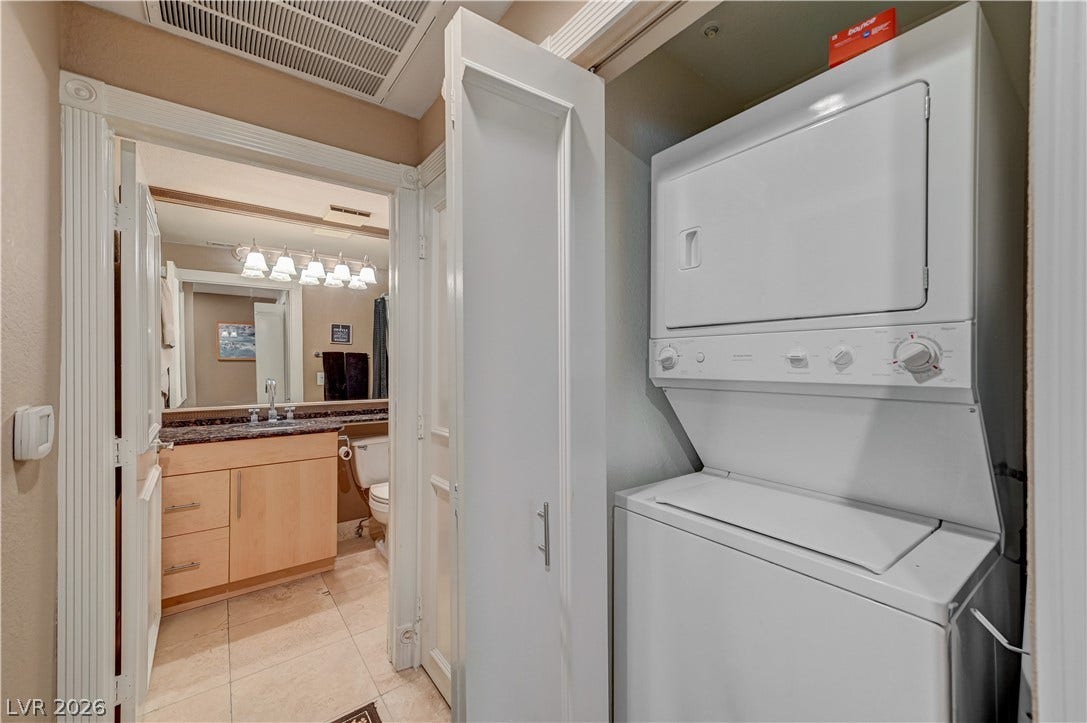 An efficient laundry closet opens directly off the tiled hallway leading to the bathroom.