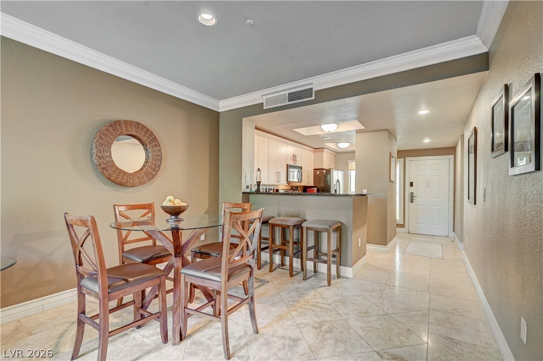 Polished tile flooring and elegant crown molding define this open dining space and entry corridor.