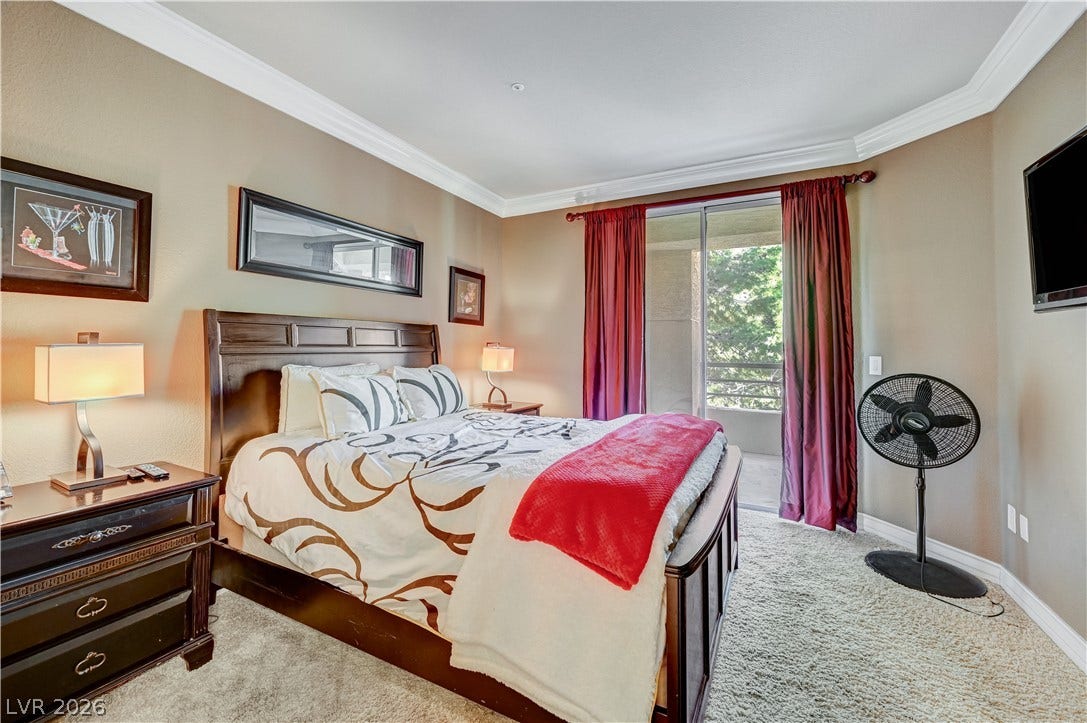 Elegant crown molding complements plush carpeting and sliding doors opening to a private balcony.