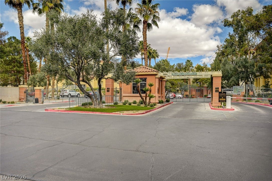 Mature palms and manicured landscaping frame a secure, gated entry to this exclusive community.