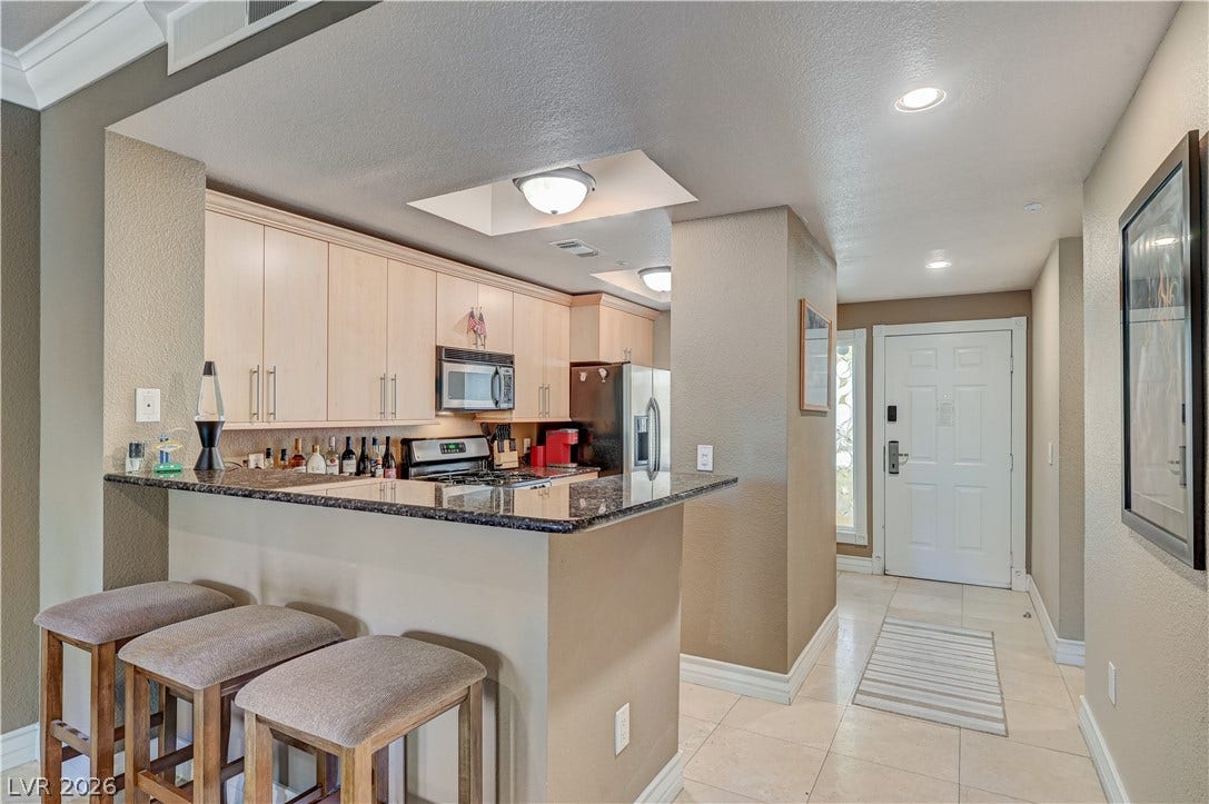 Polished granite countertops and classic crown molding accent this welcoming entryway and kitchen area.