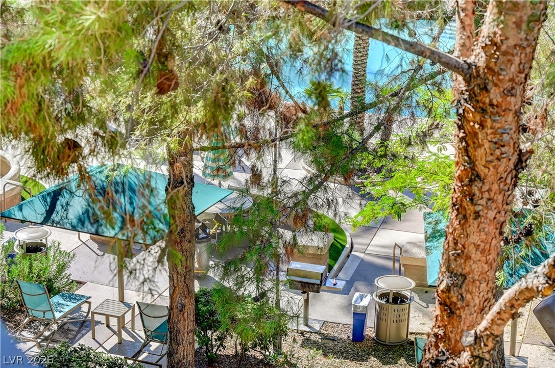 Mature trees frame a view of the community pool and shared patio areas below.