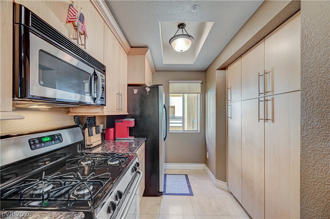 Functional kitchen design showcases flat-panel wood cabinetry alongside durable stone countertops.