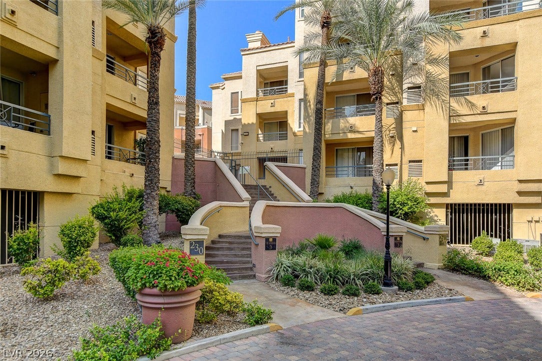 Stately stucco exteriors surround a landscaped central courtyard with palm trees and stone pathways.