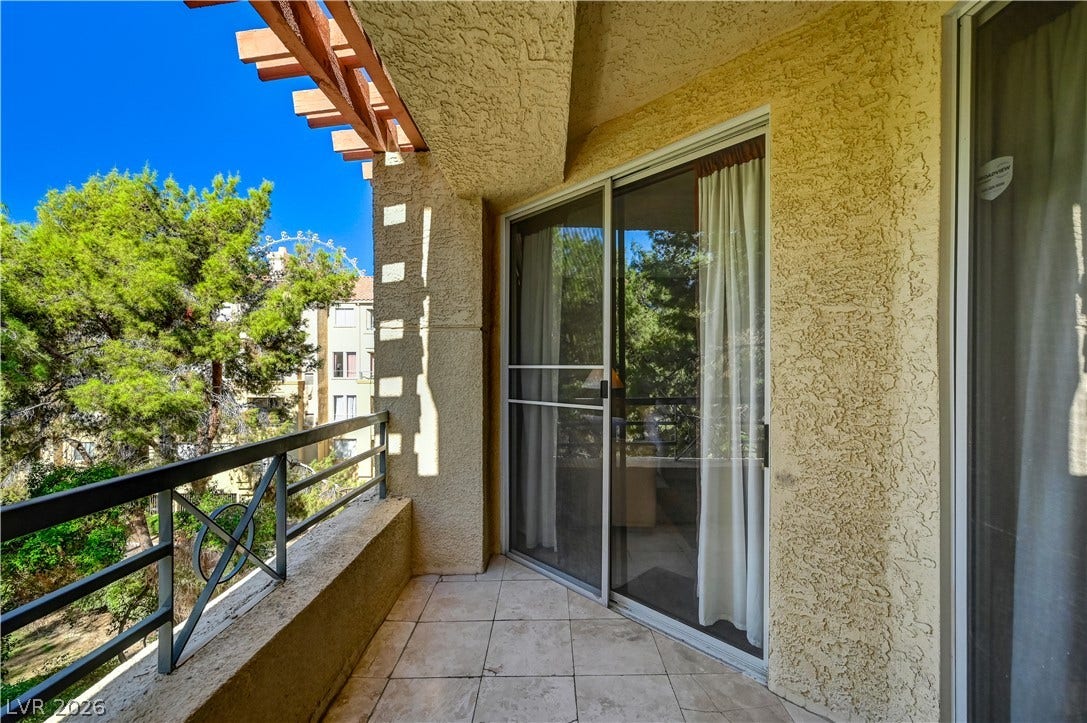 Sliding glass doors open onto a private tiled balcony framed by classic stucco finishes.