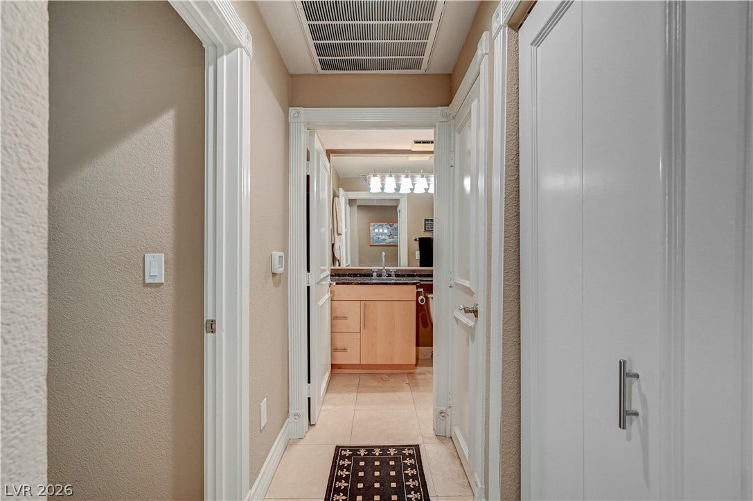 Crisp white trim work borders neutral walls leading toward an adjacent bathroom space.