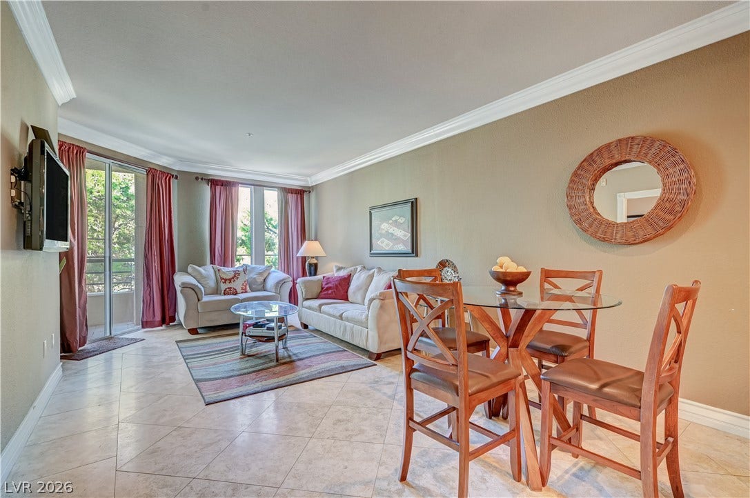 Crown molding frames the open-concept living area, seamlessly connecting the dining space with the sunlit lounge.