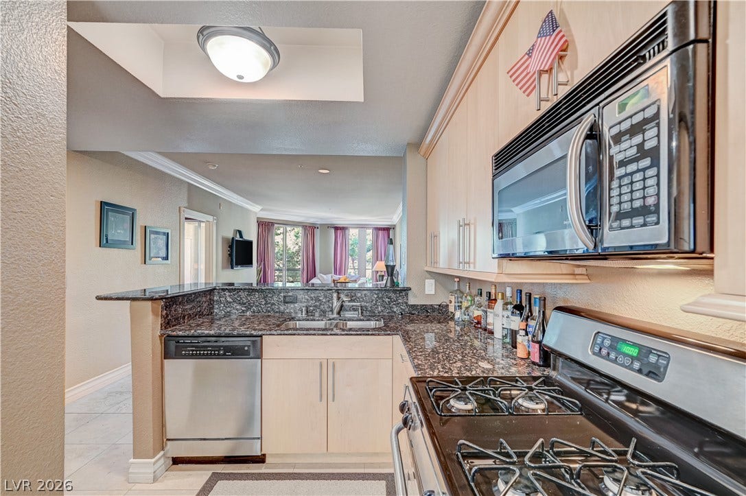 Granite countertops and light wood cabinetry anchor this functional cooking space overlooking the main living area.