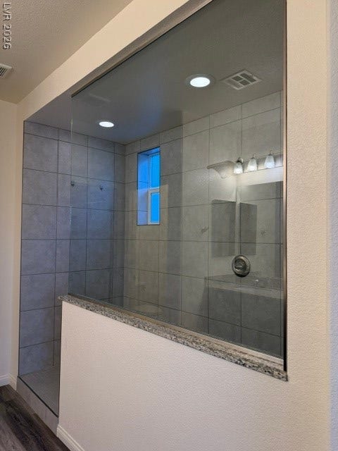 10764 Canary Blossom Avenue, Las Vegas, NV 89129 Floor-to-ceiling tiles and a frameless glass enclosure define this contemporary walk-in shower.
