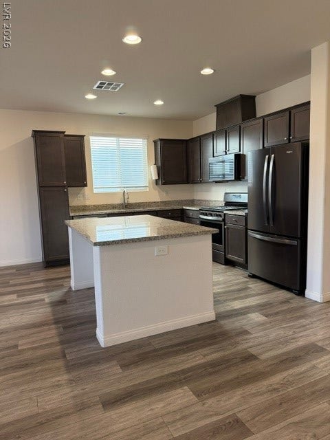 10764 Canary Blossom Avenue, Las Vegas, NV 89129 Rich dark cabinetry pairs beautifully with stone countertops and warm wood-style flooring.