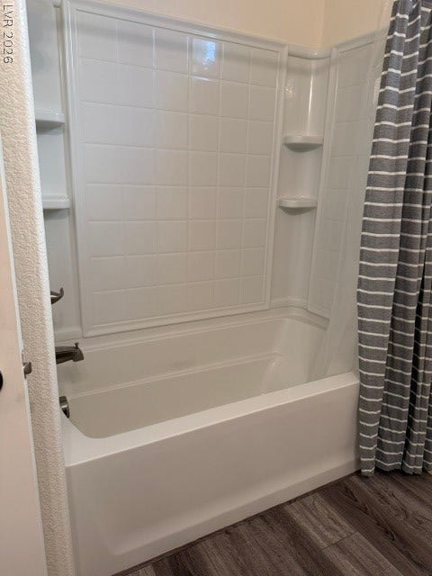 10764 Canary Blossom Avenue, Las Vegas, NV 89129 A clean bathtub and shower combination features white surround paneling and vinyl plank flooring.