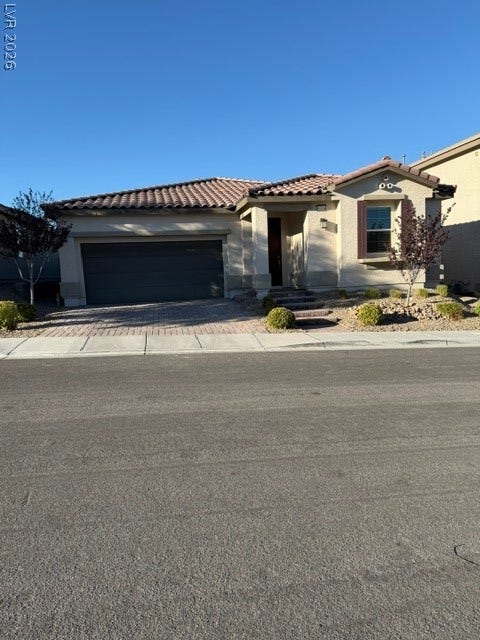10764 Canary Blossom Avenue, Las Vegas, NV 89129 A classic stucco exterior features a tiled roof and an attached garage under clear skies.