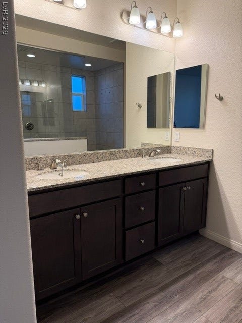 10764 Canary Blossom Avenue, Las Vegas, NV 89129 Double vanities with stone counters flank dark cabinetry on durable plank flooring.