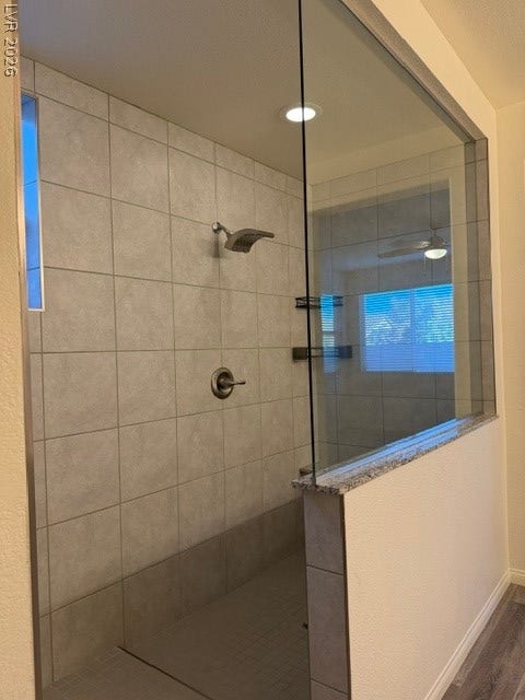 10764 Canary Blossom Avenue, Las Vegas, NV 89129 A glass-enclosed walk-in shower showcases custom tile surrounds and built-in stone ledge detailing.