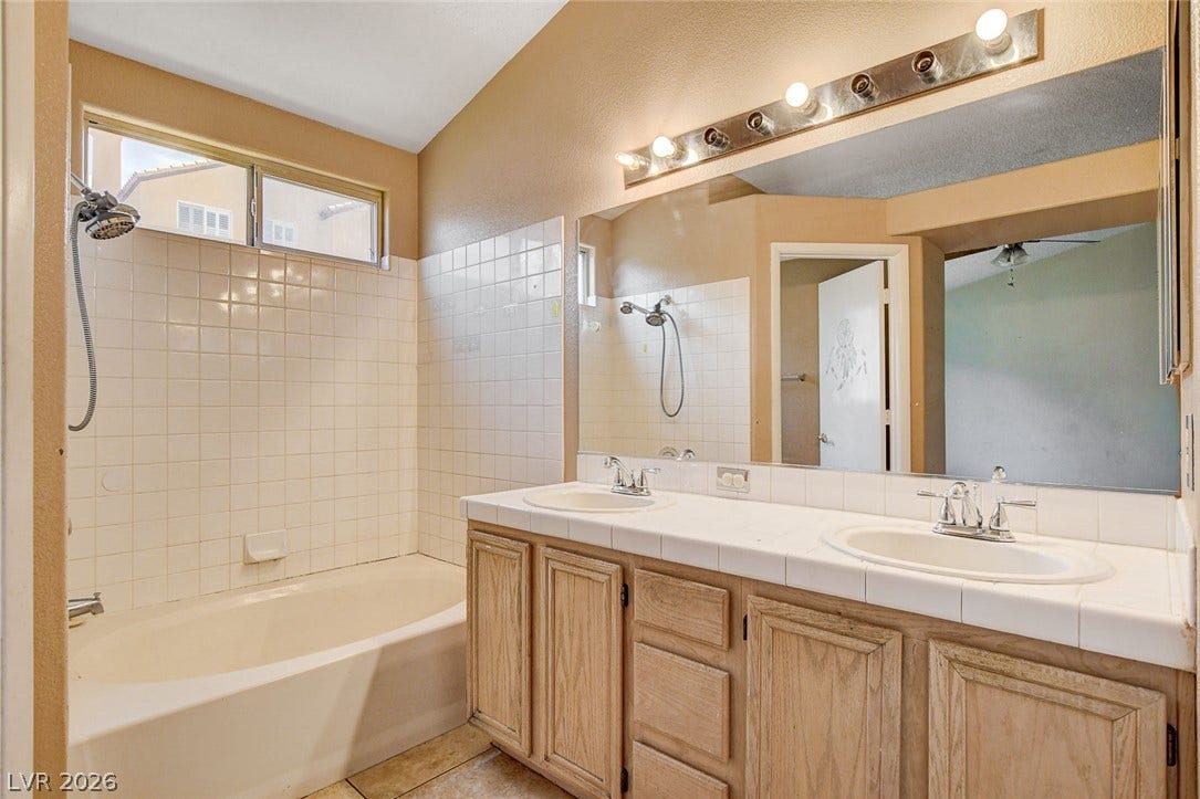 811 Rio Poco Court, Henderson, NV 89015 A spacious double vanity matches the tiled tub and shower combo under vaulted ceilings.