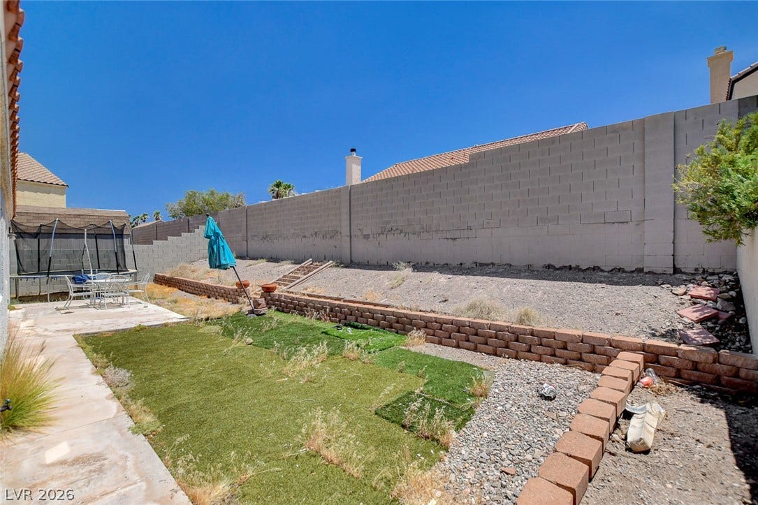 811 Rio Poco Court, Henderson, NV 89015 An enclosed backyard features terraced retaining walls beneath a clear blue sky.