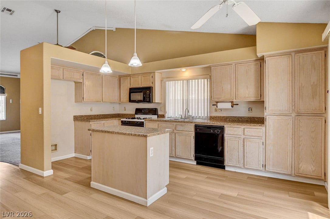 811 Rio Poco Court, Henderson, NV 89015 Warm wood flooring meets matching cabinetry beneath vaulted ceilings in this functional cooking space.