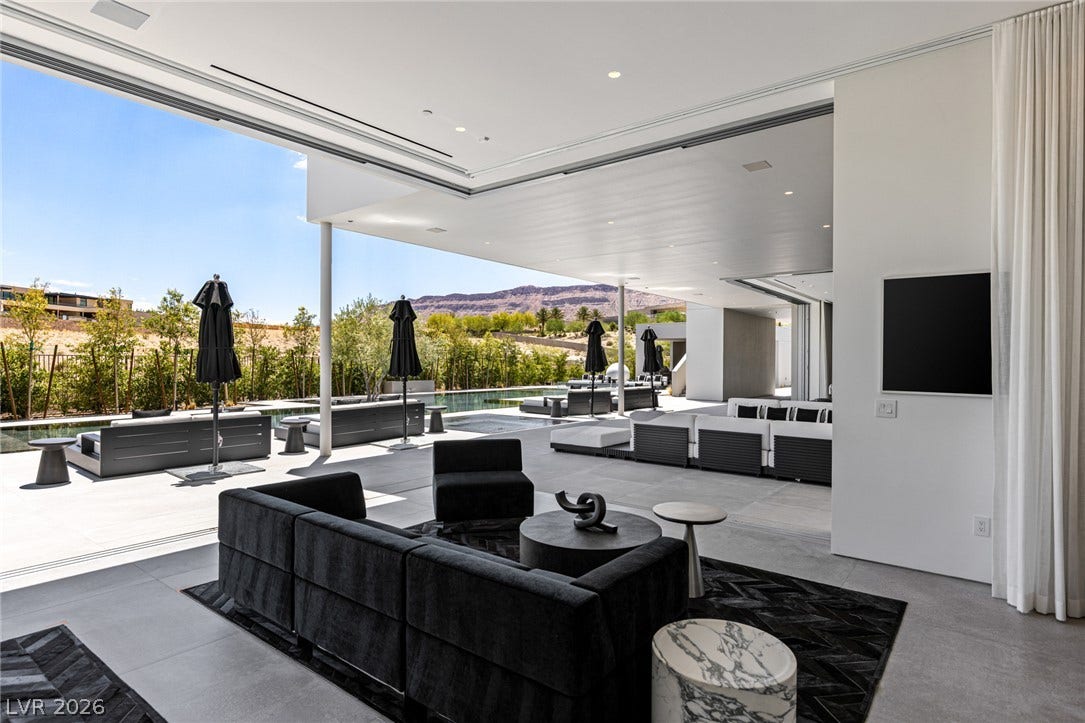 An entertainer's dream, this modern outdoor living space seamlessly merges with interior comfort, overlooking a serene pool and distant mountains.