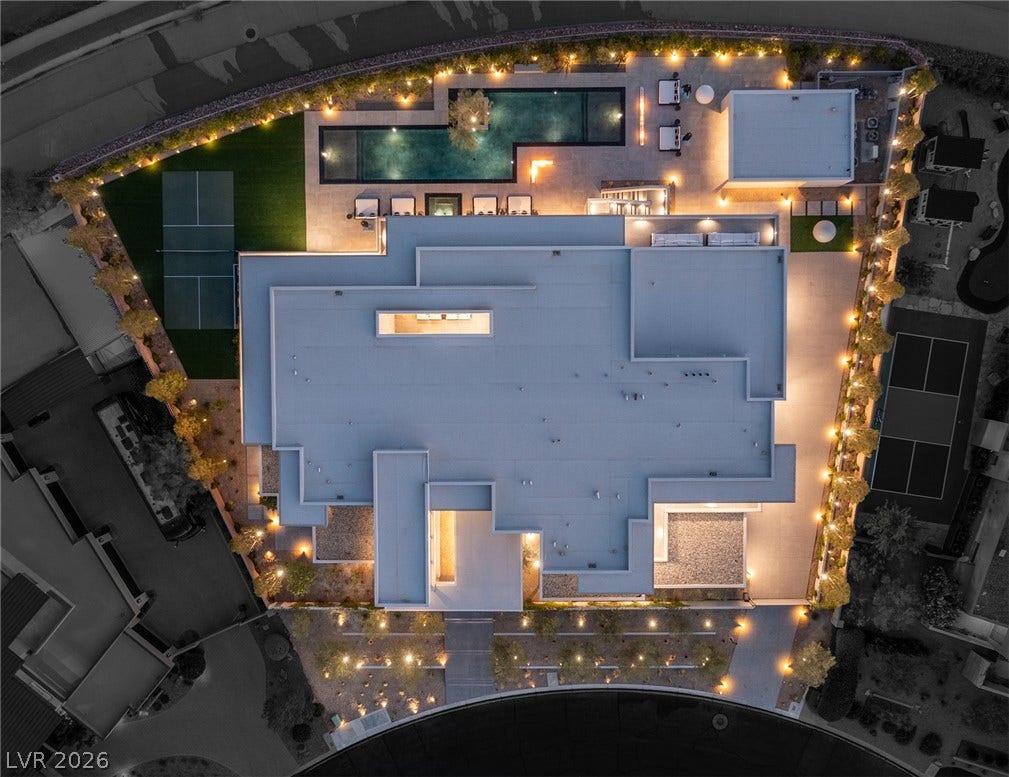 An aerial perspective reveals a modern architectural marvel with extensive outdoor recreation and lighting.