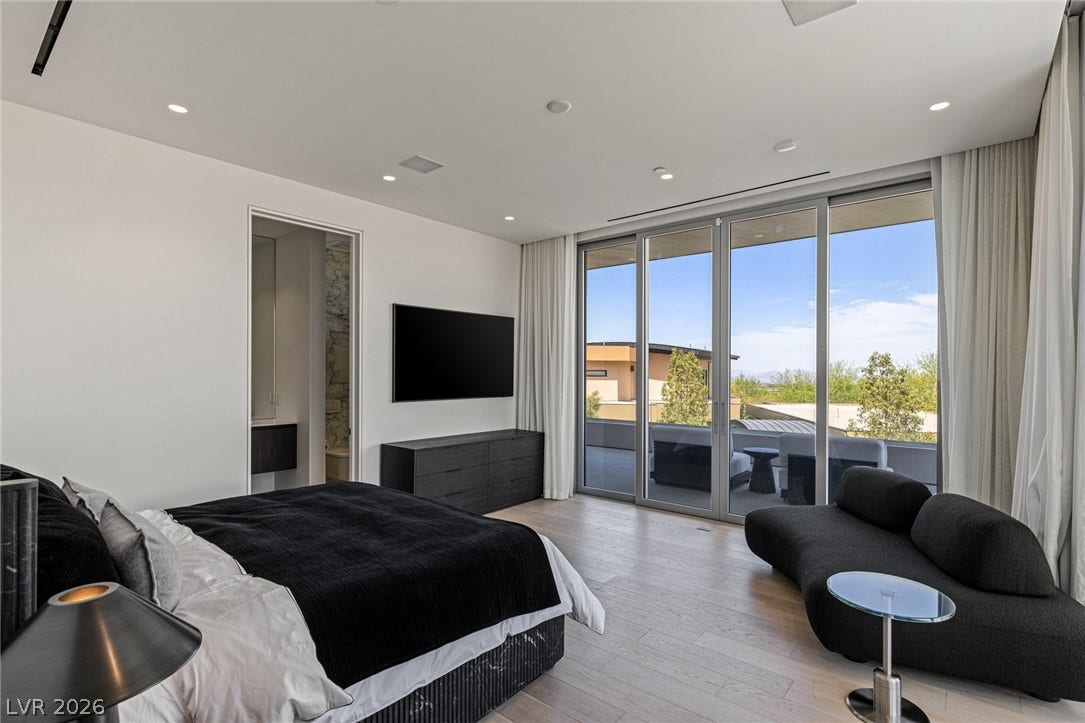 Floor-to-ceiling windows offer expansive views from this primary bedroom with direct outdoor access.