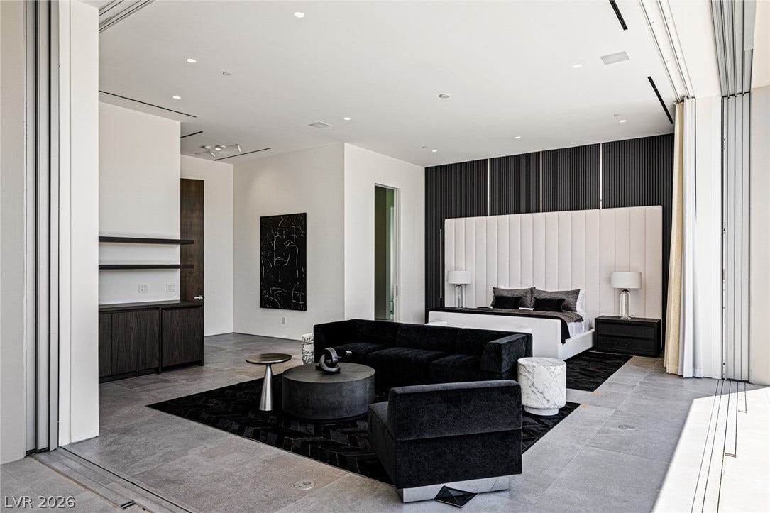 A spacious primary bedroom features concrete floors, high ceilings, and recessed lighting.