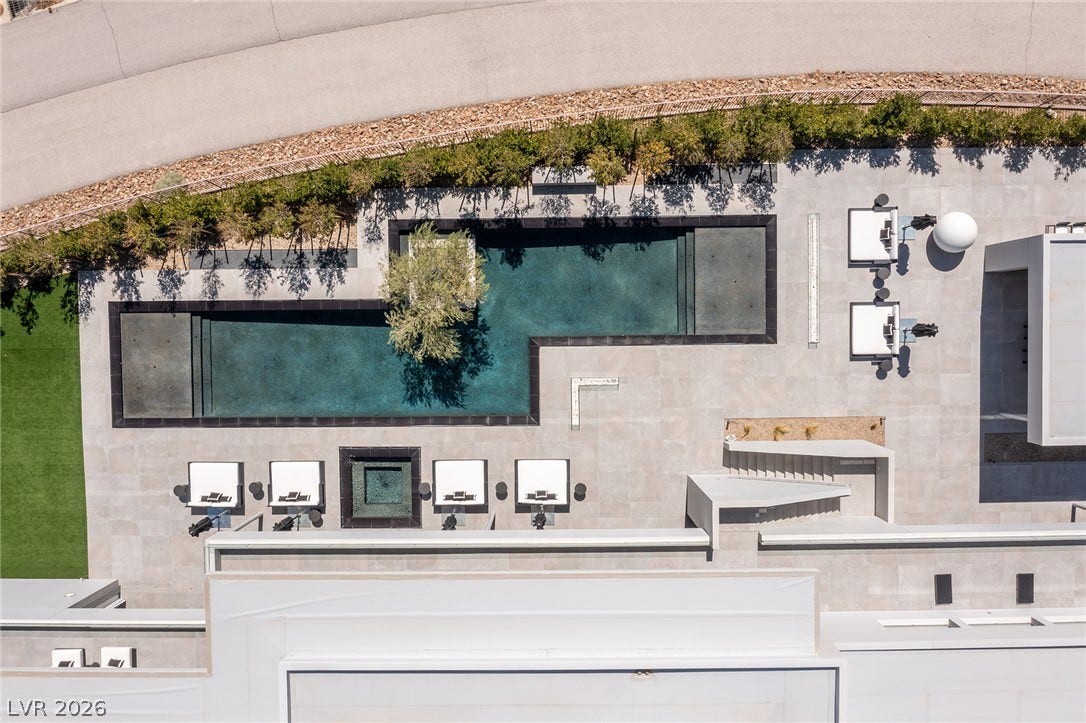 An aerial perspective reveals a private, contemporary pool area with sleek design and lush landscaping.