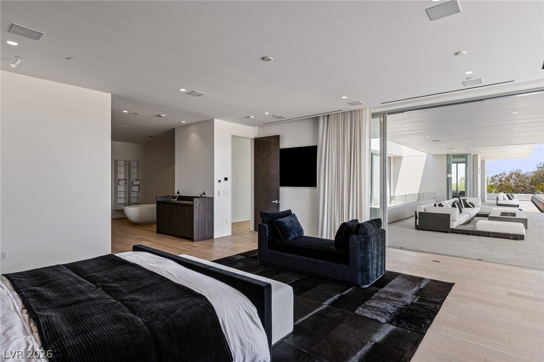Hardwood floors and recessed lighting elevate this primary bedroom, leading to an expansive outdoor patio.