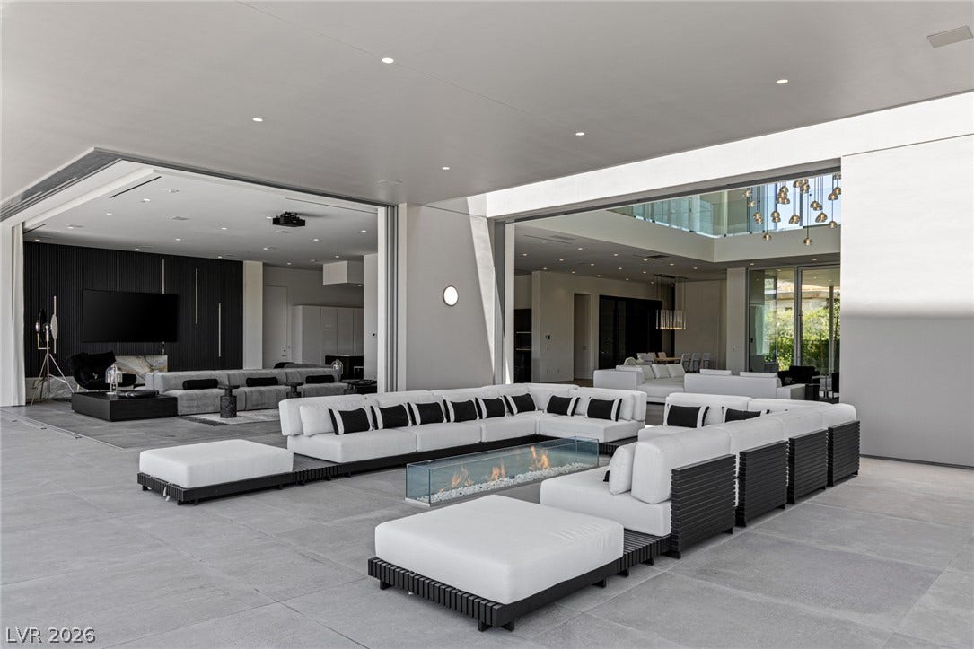 An inviting outdoor living space features an open-air fireplace, perfect for entertaining.