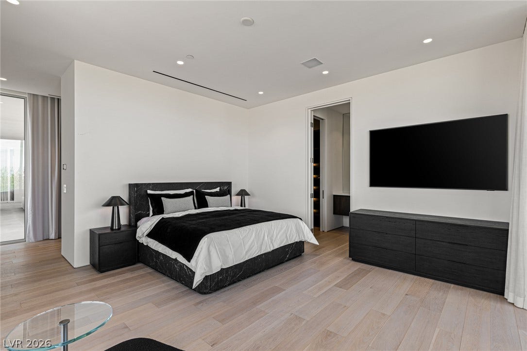 Blonde hardwood floors flow through this well-lit primary bedroom with outdoor access and a walk-in closet.