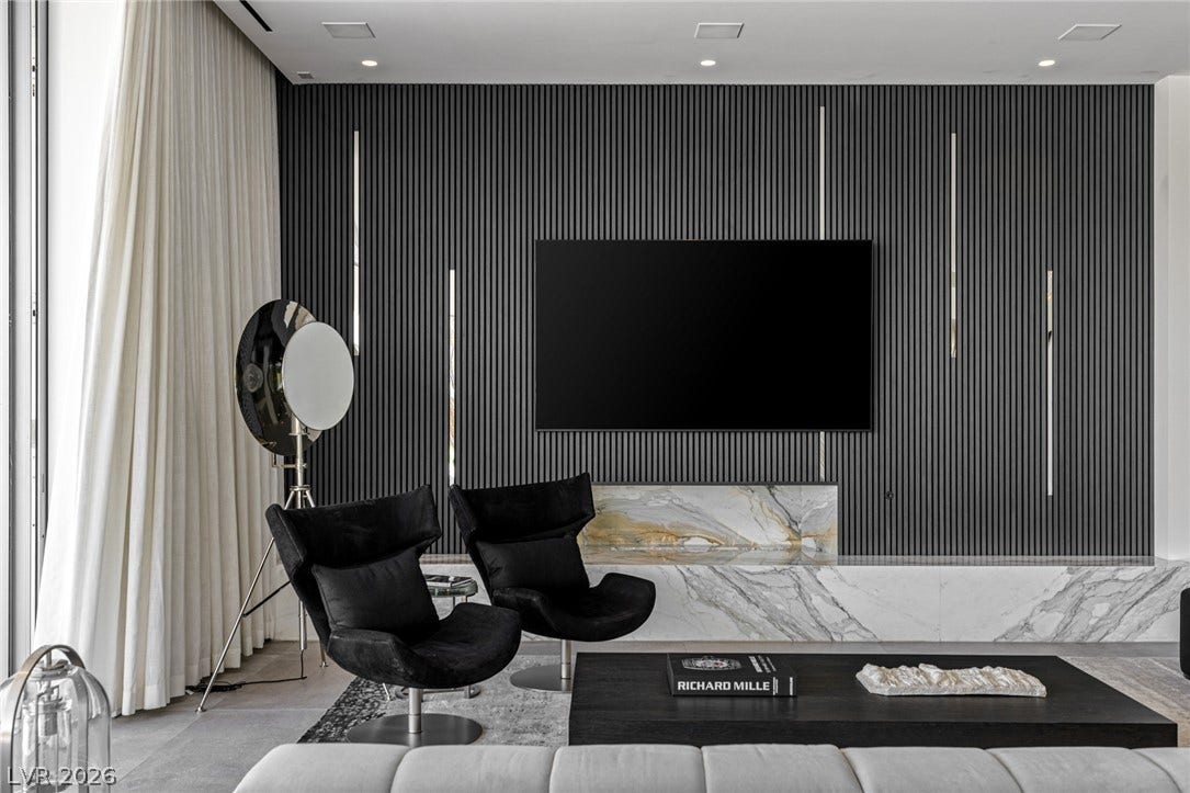 A refined living area presents a distinctive paneled accent wall and a polished marble-clad media console.