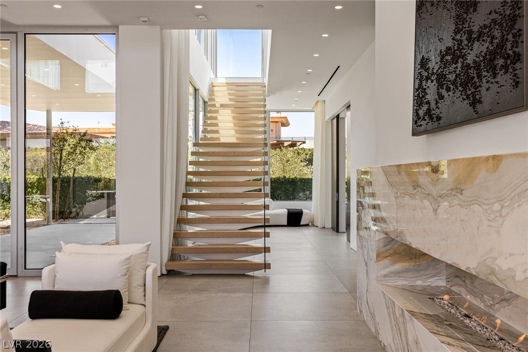 Floor-to-ceiling windows and a sleek floating staircase highlight this contemporary entryway.