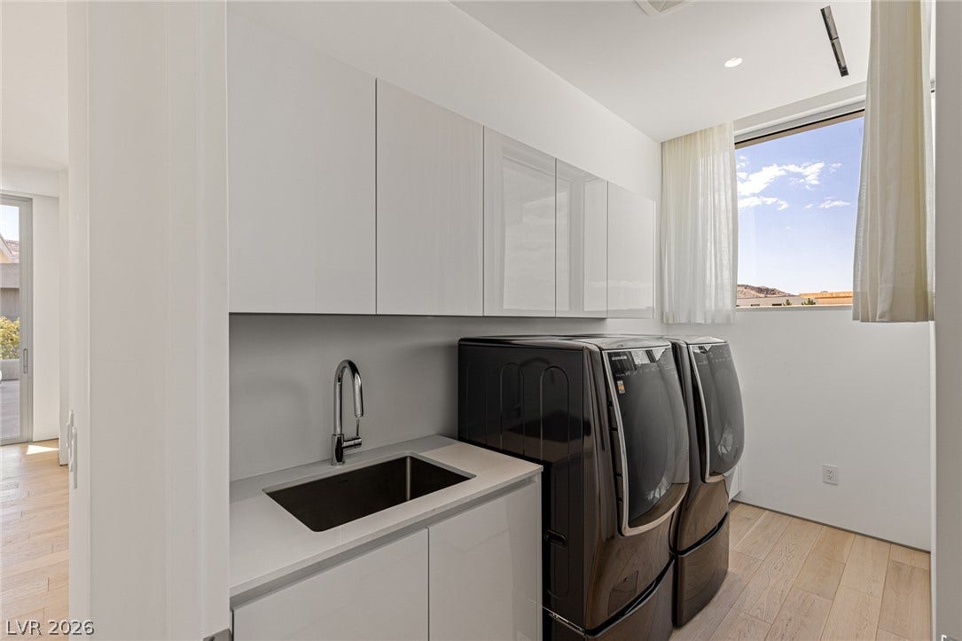 A well-appointed laundry room features modern appliances, a practical sink, and abundant natural light.