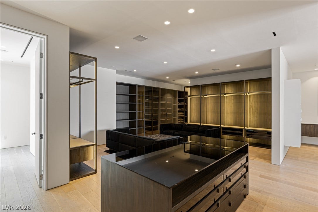 A well-appointed dressing room showcases extensive custom built-in storage and sleek wooden flooring.