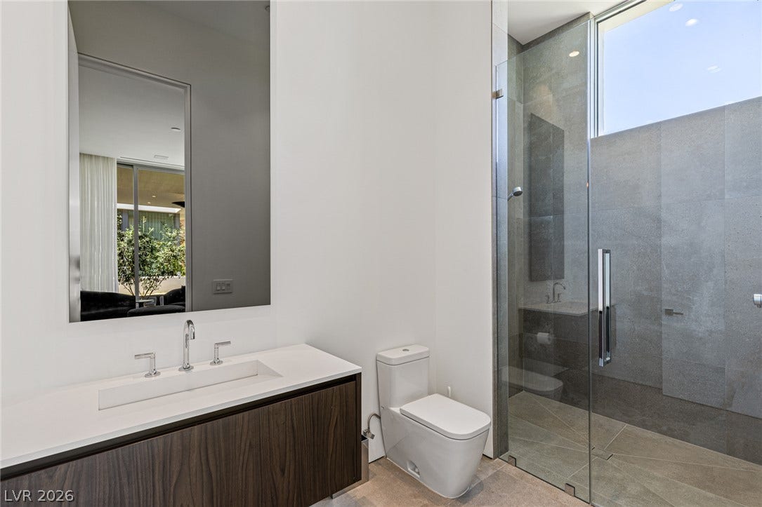 A well-appointed bathroom features a modern vanity with a large mirror and a spacious walk-in shower.