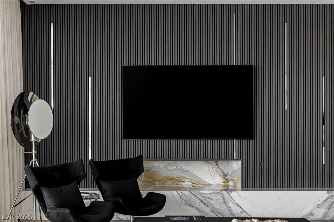 A refined living area presents a sleek wall-mounted television above an elegant marble console.