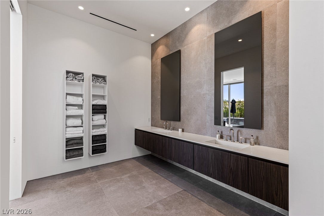 A well-lit, contemporary primary bathroom features a floating dual vanity and floor-to-ceiling mirrors.